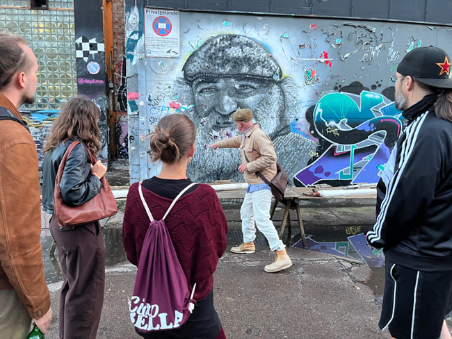 Street art-tour Berlijn, Martin Boose geeft uitleg over een grote muurschildering aan een groep